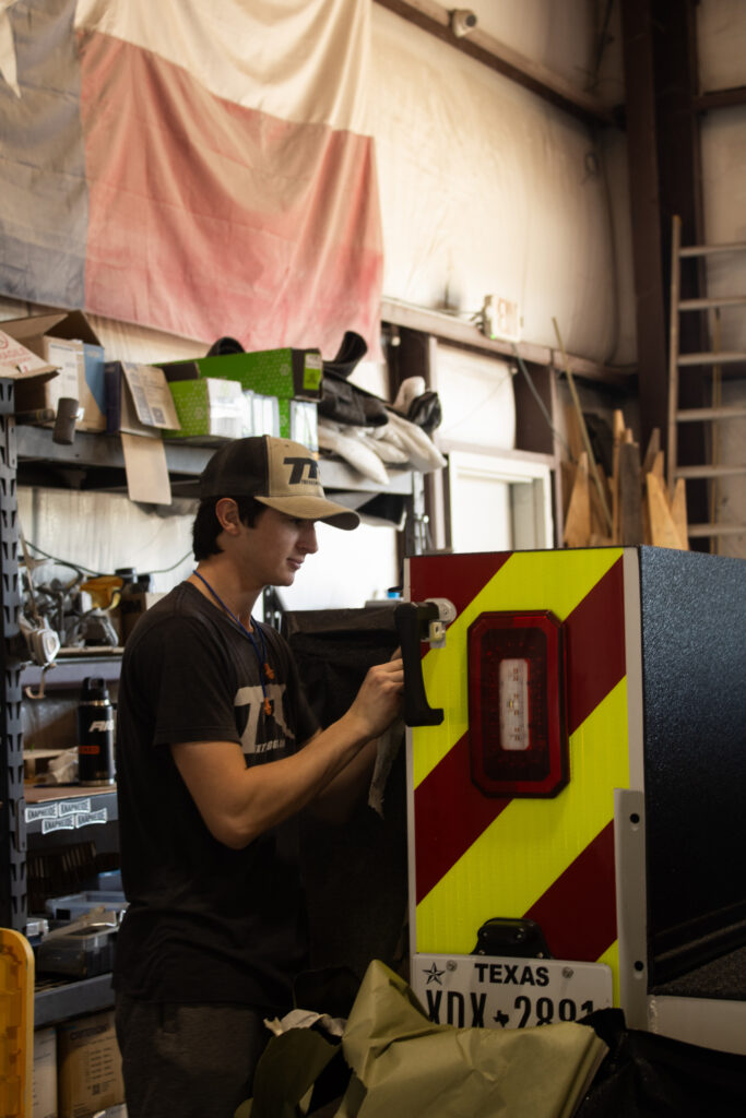 Texas Truck Riggins technician carefully removing protective masking from a freshly sprayed custom truck service body in Bryan, TX.