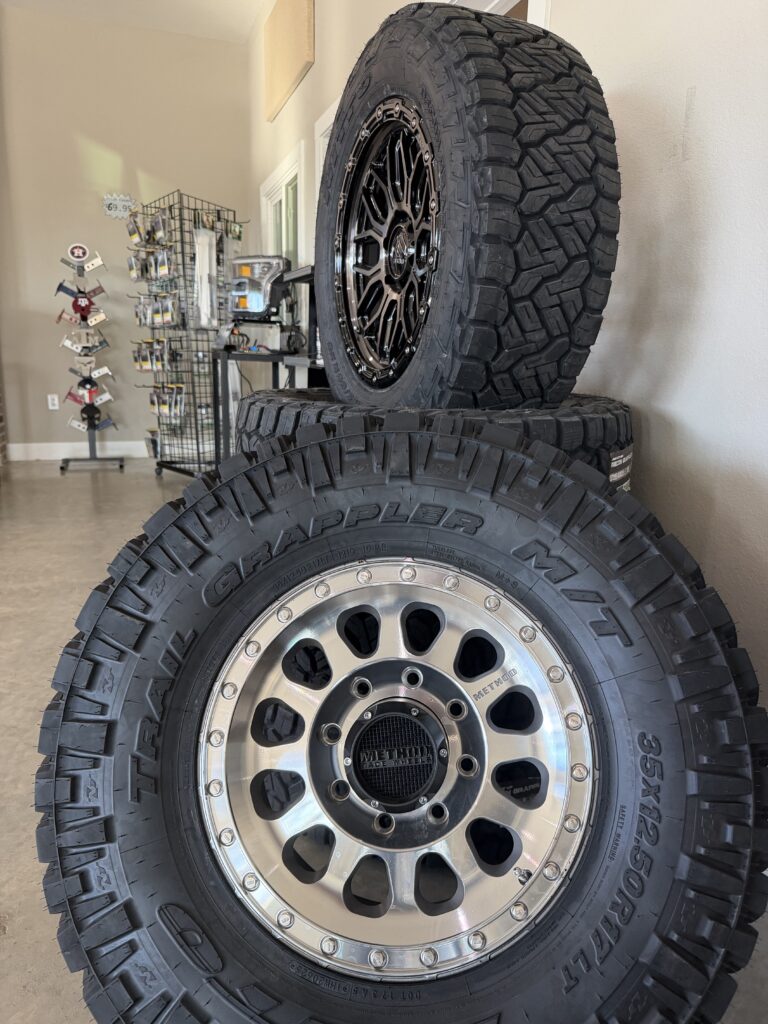Method wheel and tire displayed in front of a stack of tires.