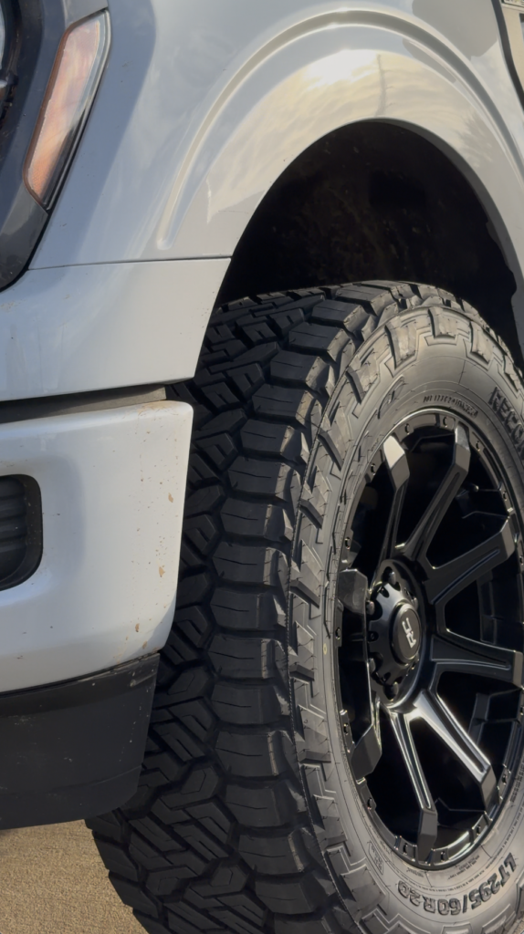 Close-up of a white truck's front left wheel.